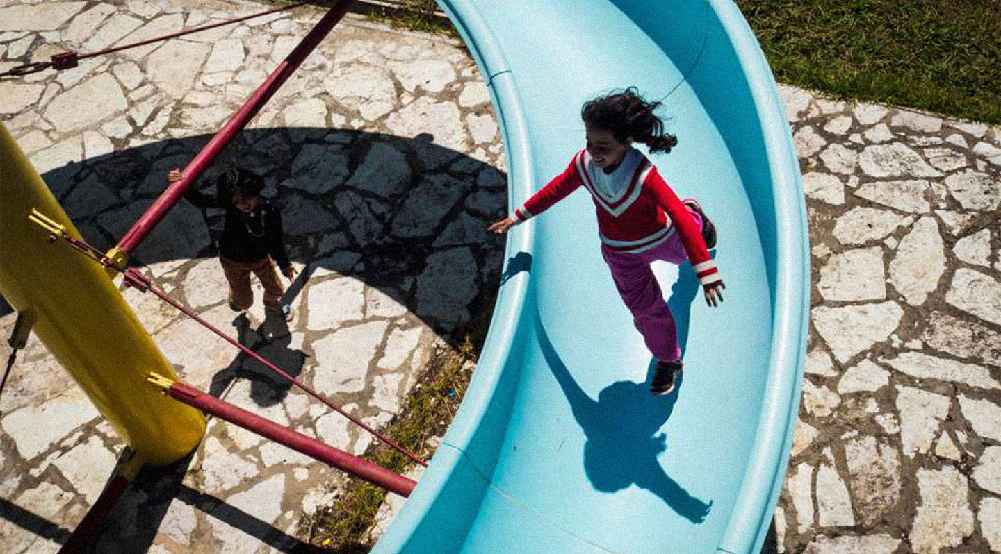 <p>Syrian refugees Hala and Zeina play on a disused water slide inside LM Village Resort, closed as a result of Greece’s financial crisis. Photo: UNHCR/Achilleas Zavallis</p>
